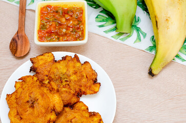 Patacones or fried tostones of green or ripe plantain, crispy, with tomato and onion stew called 