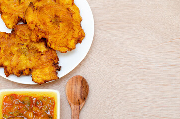 Patacones or fried tostones of green or ripe plantain, crispy, with tomato and onion stew called 