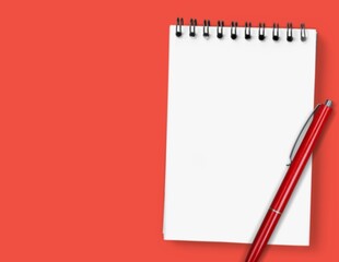 Notepad for writing text with pen on a red background.