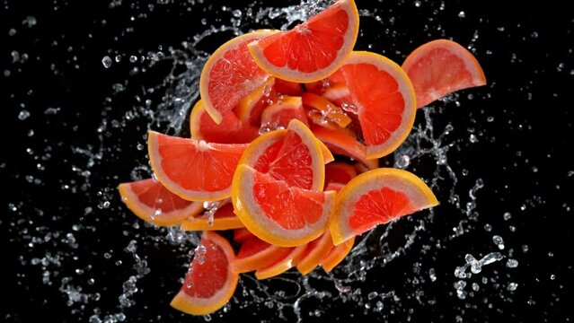 Super slow motion shot of rotating exploded grapefruit slices and water on black at 1000fps.