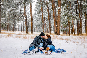 Fototapeta na wymiar Man and Woman Kissing Surrounded by Snowy Pine Trees