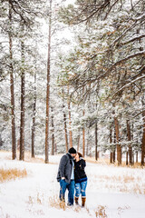 Fototapeta na wymiar Man and Woman Kissing in a Snowy Pine Forest