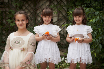 Communion girl posing with her twin little sisters in a park