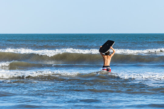 Teenage Boy With Black Bodyboard in the Ocean