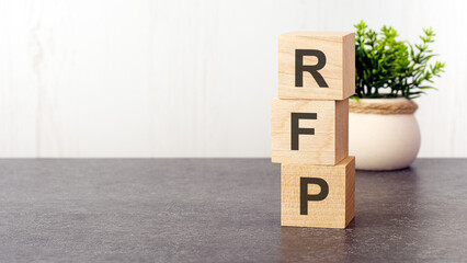 letters of the alphabet of RFP on wooden cubes, green plant, white background