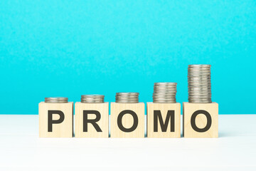wooden blocks with text promo and coins on wooden table. copy space. blue background