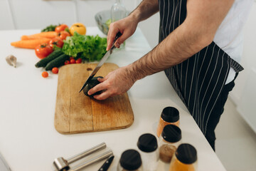 A man slices an avocado in the kitchen Food on the kitchen table.