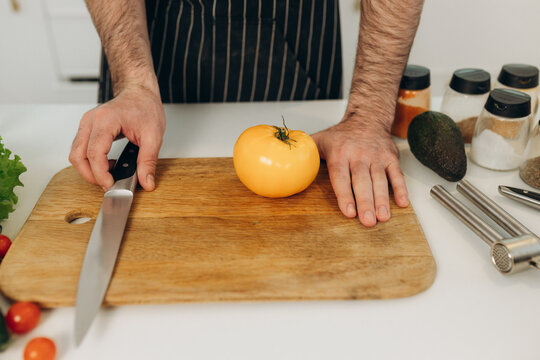 Close-up portrait of a kitchen knife with a yellow tomato. Cooking
