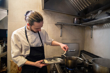 chef cuece tortelini pasta fresca con salsa tradicional y queso en cocina de restaurante italiano