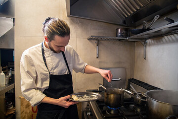 chef cuece tortelini pasta fresca con salsa tradicional y queso en cocina de restaurante italiano