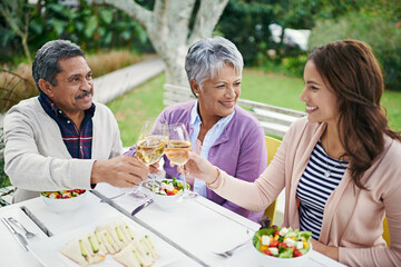 They love it when their daughter comes to visit. Cropped shot of a family toasting over their lunch while sitting outside.