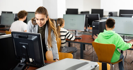 Fototapeta premium Young woman teacher using PC during computer science lesson.