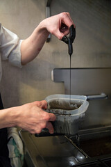 chef tempura de verduras con tinta de calamar frie en freidora de cocina en restaurante close-up manos