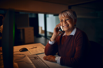 My deadlines are nearly done and then Ill be home. Shot of a mature businesswoman talking on a cellphone while working late in an office.