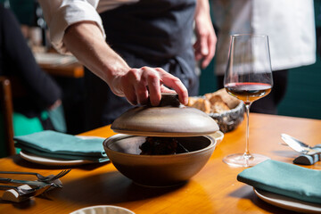 Fototapeta na wymiar Tempura de verduras con tinta de calamar y salsa de pimiento rojo close-up, servido en una mesa de un restaurante por un camarero con un mandil negro y camisa blanca