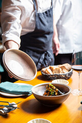 Tempura de verduras con tinta de calamar y salsa de pimiento rojo close-up, servido en una mesa de un restaurante por un camarero con un mandil negro y camisa blanca