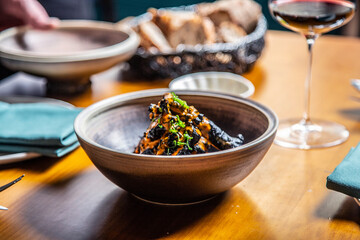 Tempura de verduras con tinta de calamar y salsa de pimiento rojo close-up, servido en una mesa de un restaurante por un camarero con un mandil negro y camisa blanca