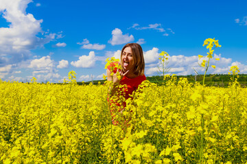 Young pretty woman in a colored dress on Lightning cheerful yellow background blooming rapeseed...
