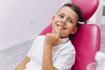 A boy in a dental chair shows the dentist a tooth he wants to treat.