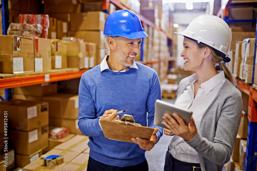 Poster orders sorted. shot of two managers looking at stock in a large warehouse.
