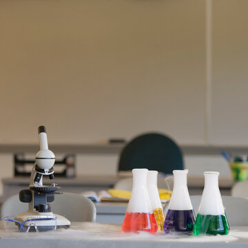 Chemistry equipment on laboratory bench, microscope and beakers.