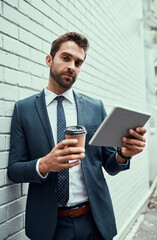 Handling all his business matters on the move. Portrait of a handsome young businessman using a digital tablet outdoors.