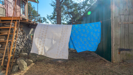 Bedding sheets drying on the clothesline outside. Lens flare. Bed linen drying on a clothes line in the garden.