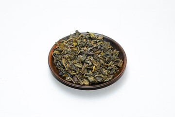dry green tea leaves in wooden bowl on white background