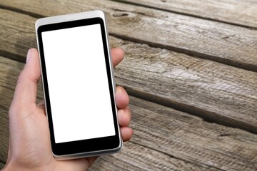 Human holding a smartphone on the screen. Rustic wooden table.