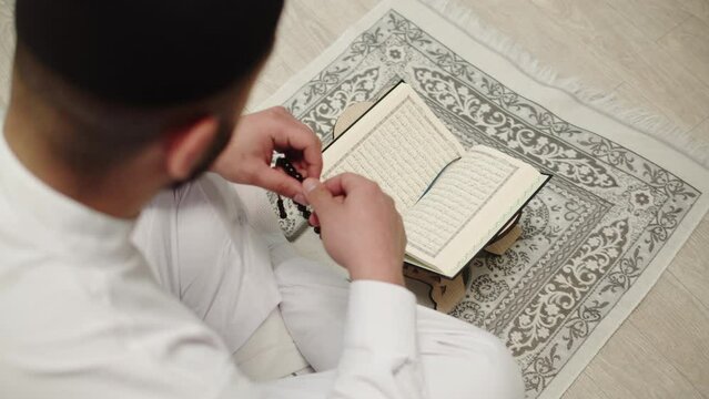 Man praying, reading Koran close-up, islamic religion. Religious holiday Ramadan, holy month. Muslim worship, male person making traditional prayer to God.