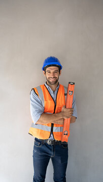 Portrait of a handsome European Middle Eastern engineer smiling, wearing a hard hat, reflective vest, holding a magnetic water level.background image banner civil engineering concept working people.