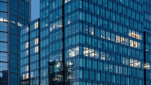 Time lapse day to night transition blinking office windows lights in business center building downtown. Corporate business, high skyscraper glass surface. Light in building windows turn on and off
