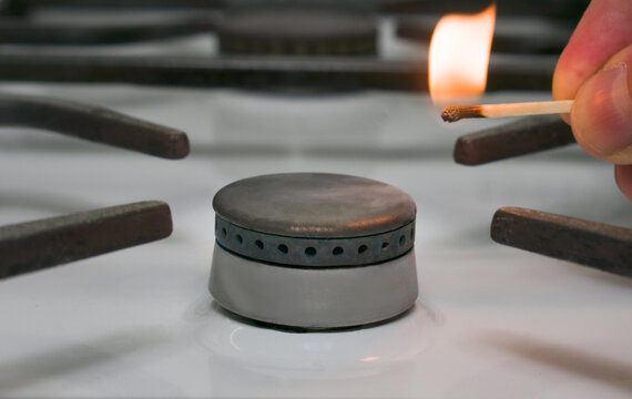 Turned off kitchen stove being lightened by a lit match