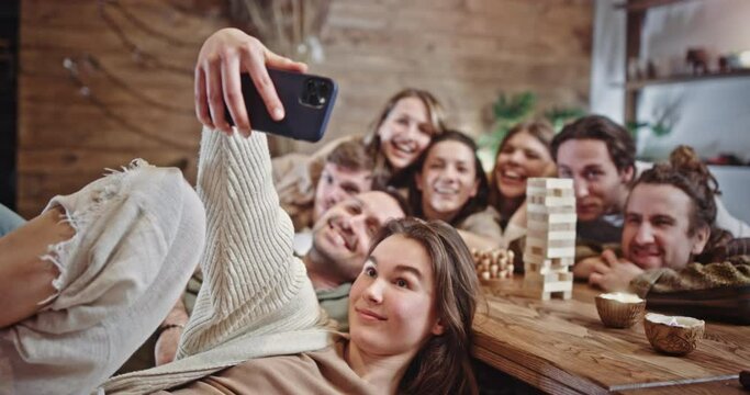 Group of diverse friends posing for a selfie on a mobile phone. Group of happy smiling diverse young friends posing for a selfie on a mobile phone gathered round a table in a restaurant