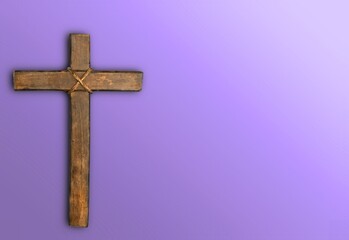 Wooden christian cross on purple background.