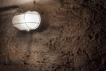 Concrete wall under Industrial old ceiling lamp light. Old vintage basement interior, grunge urban...