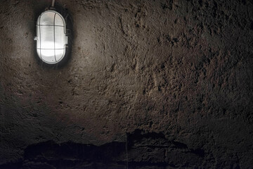 Concrete wall under Industrial old ceiling lamp light. Old vintage basement interior, grunge urban underground background.