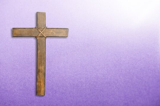 Wooden christian cross on purple background.
