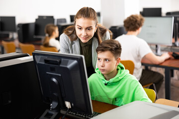 Teacher together with students conduct a lesson on computer education