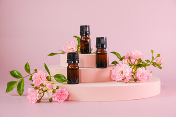 Rose essential oil.Aromatherapy and cosmetics. Glass brown bottles set and pink rose flowers on a...