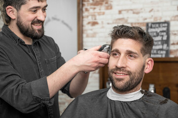 Obraz premium Closeup of happy man getting an haircut, in hair salon. High quality photo.