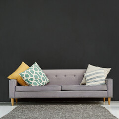 Functional and stylish for your office or home. Shot of a gray sofa with cushions against a black background.