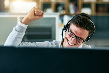Hes mastered the best way to sell the companys brand. Shot of a young call centre agent cheering...