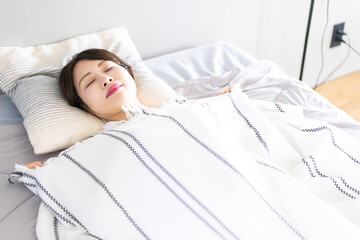 ベッドで熟睡する若い女性