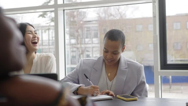 Slow motion of multiethnic businesswomen discussing and laughing in creative business meeting