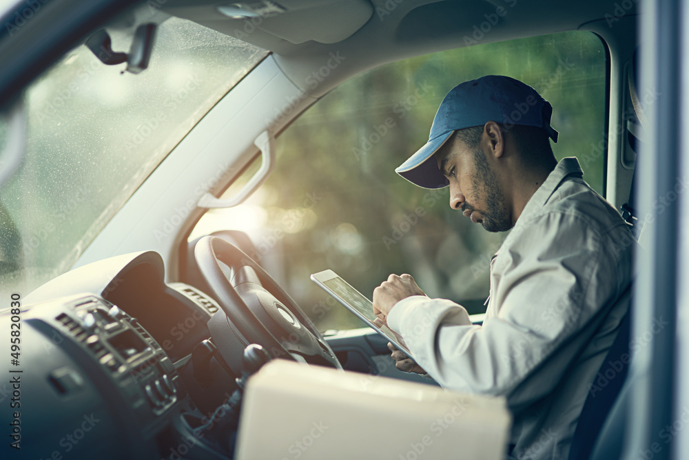 Poster scheduling his deliveries for the day. cropped shot of a delivery man using a digital tablet while s