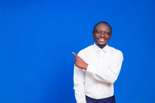 Portrait image of a black African smiling business entrepreneur pointing finger at left direction