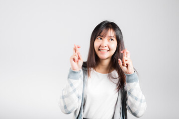 Happy woman have superstition her holding fingers crossed for good luck gesture, Asian beautiful young female smiling superstition, studio shot isolated on white background with copy space