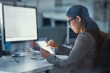 I can do my work from multiple devices. Shot of a young businesswoman working late in the office.