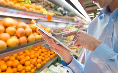 Retail management. Worker hands holding tablet on blurred supermarket